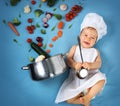 Baby boy in chef hat with cooking pan and vegetables Royalty Free Stock Photo