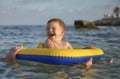 The baby boy child in the bouncy yellow circle swim in the sea