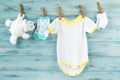 Baby boy clothes, onesie with socks and white bear toy on a clothesline Royalty Free Stock Photo