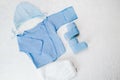 Set of baby boy clothes for newborn on a white background. Blue undershirt, knitted booties, cap and bodysuit. Royalty Free Stock Photo