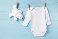 Baby boy clothes and white bear toy on a clothesline, blue background Royalty Free Stock Photo