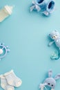 Baby boy concept. Top view vertical photo of booties socks soother teddy bear toy teether milk bottle and knitted bunny rattle toy Royalty Free Stock Photo