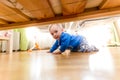 Baby boy crawling on floor and looking under the bed Royalty Free Stock Photo