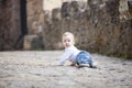 Baby boy crawling on stone paved sidewalk