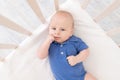 A baby boy in a crib lies on his back, a happy newborn wakes up in the morning or goes to bed Royalty Free Stock Photo