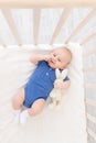 A baby boy in a crib lies on his back, a happy newborn wakes up in the morning or goes to bed Royalty Free Stock Photo