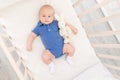 A baby boy in a crib lies on his back with a toy, a happy newborn wakes up in the morning or goes to bed Royalty Free Stock Photo