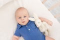 A baby boy in a crib lies on his back with a toy, a happy newborn wakes up in the morning or goes to bed Royalty Free Stock Photo