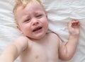 Baby boy crying lying on the bed. Royalty Free Stock Photo
