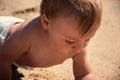 Baby boy discover sand at tropical beach close up. Curious toddler portrait who examining sand beach at summertime. Active