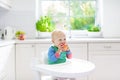 Baby boy eating apple in white kitchen at home Royalty Free Stock Photo