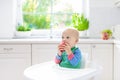 Baby boy eating apple in white kitchen at home Royalty Free Stock Photo