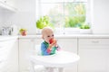 Baby boy eating apple in white kitchen at home Royalty Free Stock Photo