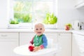 Baby boy eating apple in white kitchen at home Royalty Free Stock Photo