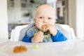Baby boy eating with BLW method, baby led weaning