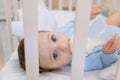 Baby boy eating from milk bottle in crib in blue bodysuit, cute little baby in bedroom, baby food concept Royalty Free Stock Photo