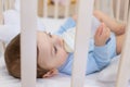 Baby boy eating from milk bottle in crib in blue bodysuit, cute little baby in bedroom, baby food concept Royalty Free Stock Photo