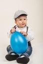 Baby boy with eyeglasses and hat playing with blue balloon