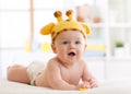 Baby boy in a funny giraffe hat lying on his belly in nursery