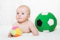 Baby boy or girl lying down on his belly and playing with soccer balls Royalty Free Stock Photo