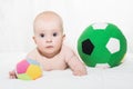 Baby boy or girl lying down on his belly and playing with soccer balls Royalty Free Stock Photo