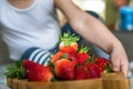 Baby boy hands touch and take raw fresh strawberries on wooden bamboo plate indoor. baby exploring fruit Royalty Free Stock Photo