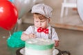 Baby boy in hat eating first birthday cake. Close-up portrait