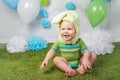 Baby boy in holiday Easter bunny rabbit costume with large ears, dressed in green clothes onesie, sitting on rug Royalty Free Stock Photo