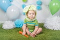 Baby boy in holiday Easter bunny rabbit costume with large ears, dressed in green clothes onesie, sitting on rug Royalty Free Stock Photo