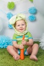 Baby boy in holiday Easter bunny rabbit costume with large ears, dressed in green clothes onesie, sitting on rug Royalty Free Stock Photo