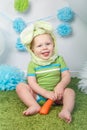 Baby boy in holiday Easter bunny rabbit costume with large ears, dressed in green clothes onesie, sitting on rug Royalty Free Stock Photo