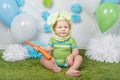 Baby boy in holiday Easter bunny rabbit costume with large ears, dressed in green clothes onesie, sitting on rug Royalty Free Stock Photo