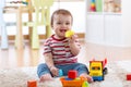 Baby infant laughing and playing with colorful toys sitting on soft carpet in nursery Royalty Free Stock Photo