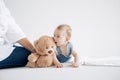 Baby boy lies and plays with toy bear near his mother Royalty Free Stock Photo