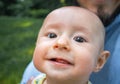 Baby boy looking at the camera and smiling close-up. Dad holds his newborn son in his arms Royalty Free Stock Photo