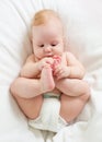 Baby boy lying on bed and holding his legs Royalty Free Stock Photo