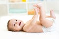 Baby boy lying on bed and holding his legs Royalty Free Stock Photo