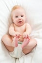 Baby boy lying on bed and holding legs Royalty Free Stock Photo