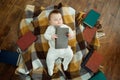 A baby boy is lying on a soft surface. There are many books around the child Royalty Free Stock Photo