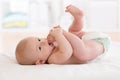 Baby boy lying on white sheet with foot in mouth Royalty Free Stock Photo