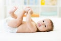 Baby boy lying on white sheet and holding his legs Royalty Free Stock Photo