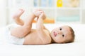 Baby boy lying on white sheet and holding his legs