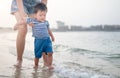 Baby boy making his first steps on the beach with his mother Royalty Free Stock Photo