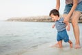 Baby boy making his first steps on the beach with his mother Royalty Free Stock Photo