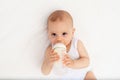 Baby boy 8 months old lies drinking milk from a bottle on the bed in the nursery, feeding the baby, baby food concept Royalty Free Stock Photo