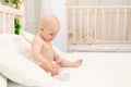 Baby boy 8 months old sitting in diapers on a white bed with a bottle of milk at home, baby food concept, first bait, place for Royalty Free Stock Photo