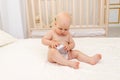 Baby boy 8 months old sitting in diapers on a white bed with a bottle of milk at home, baby food concept, first bait, place for Royalty Free Stock Photo