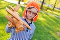 Boy in orange helmet pilot playing in toy wooden plane against grass background Royalty Free Stock Photo