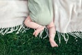 Baby boy in a pistachio muslin bodysuit on a plaid in the grass. Top view, copy space Royalty Free Stock Photo