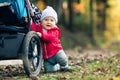 Baby boy playing in autumn forest with stroller, outdoors fun Royalty Free Stock Photo